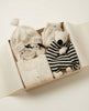Baby clothing set with hat, sweater, and toy in a box on a light background