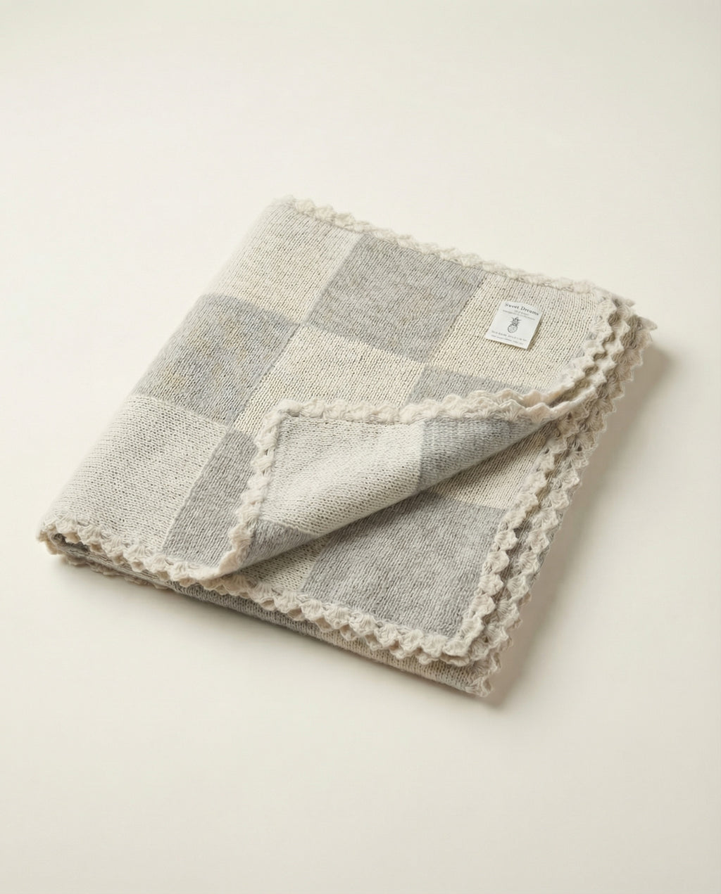 Folded checkered blanket with lace trim on a light background